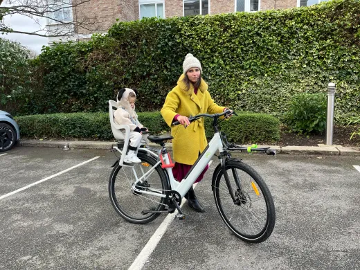 Mum standing with the CYCL compact e-bike, toddler settled in the rear child seat
